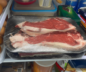 Entrecots en nevera en una bandeja dentro de la nevera