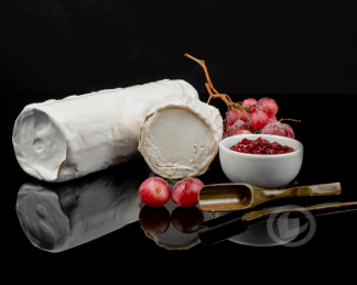 Rulo de cabra Vuelta y Vuelta. Un rulo entero, un corte, uvas negras y un bowl de mermelada de fresa