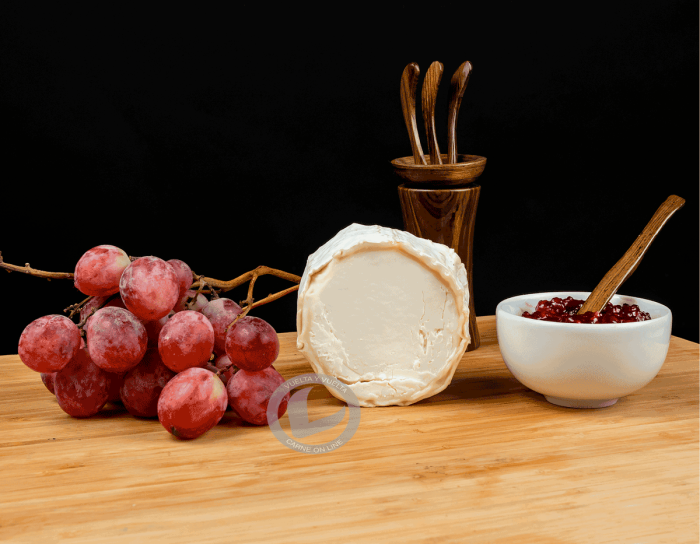 Corte de Rulo de cabra Soignon. Aparece con mermelada de frutos rojos y unas uvas.