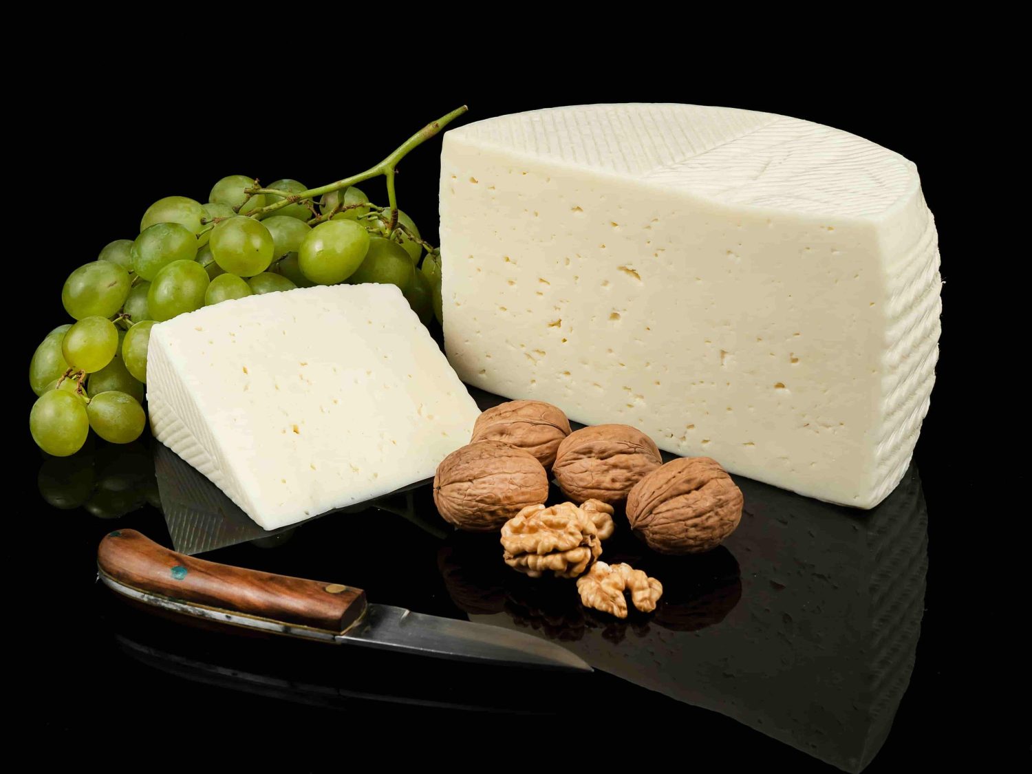 Queso manchego tierno, medio queso, cuña, navaja y nueces y uvas verdes