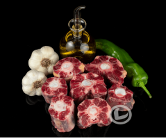 Trozos de rabo de toro, un pimiento verde, dos ajos y una aceitera de AOVE