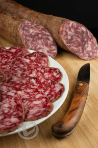 salchichón ibérico cortado en un plato y al lado una navaja