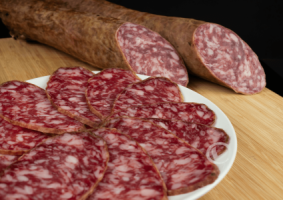 salchichón ibérico cortado en lonchas en un plato y dos barras detrás