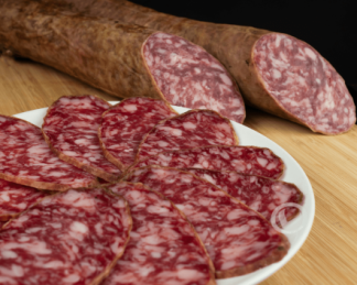 salchichón ibérico cortado en lonchas en un plato y dos barras detrás
