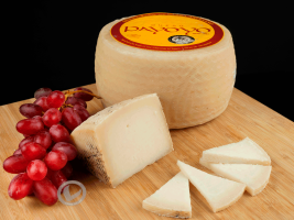 Queso payoyo de cabra, entero y también una cuña, varios cortes y un racimo de uvas negras