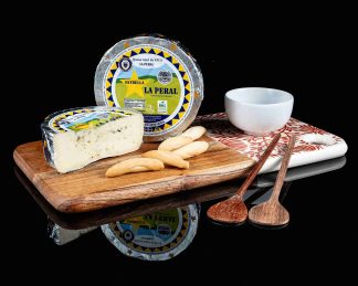 Queso entero La Peral, con medio queso sobre una tabla. Aparecen también picos y un bowl con mermelada