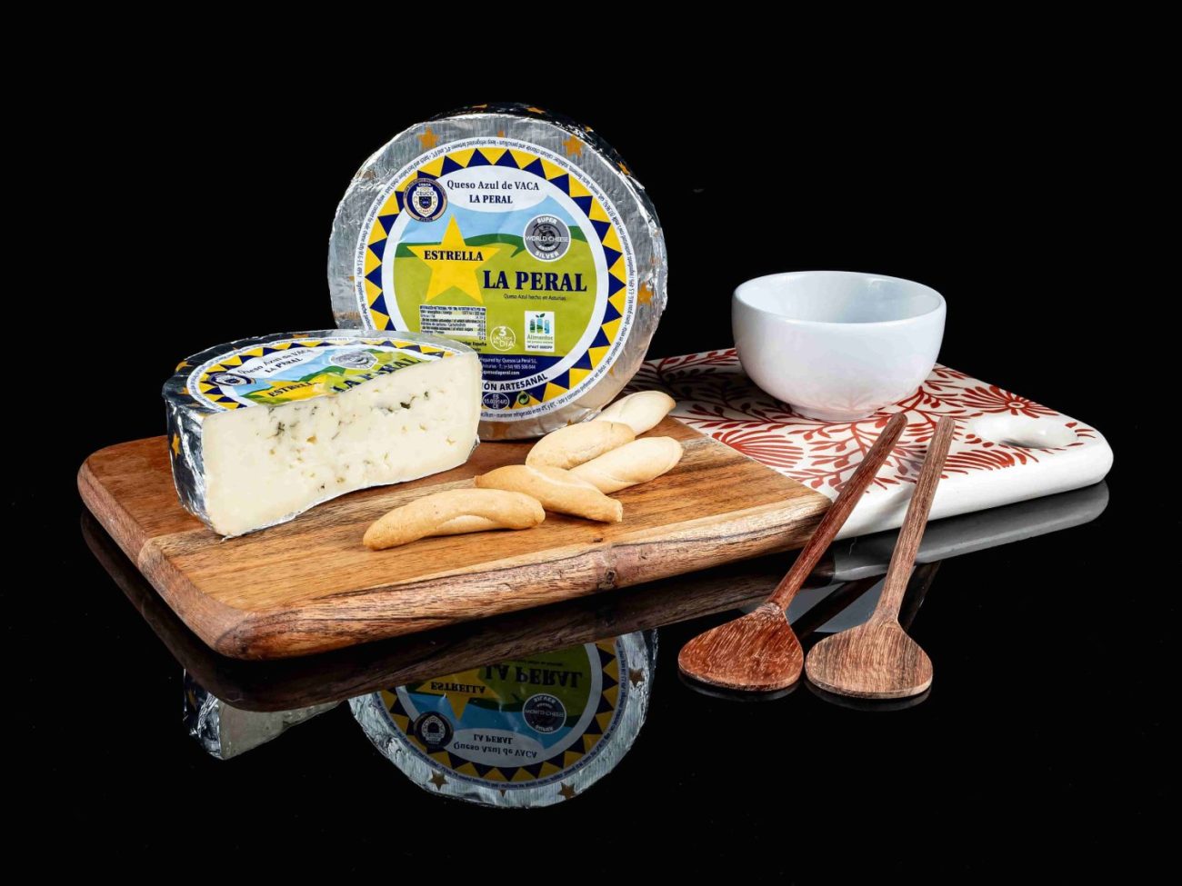 Queso entero La Peral, con medio queso sobre una tabla. Aparecen también picos y un bowl con mermelada